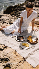 Woman enjoying fresh figs and citrus on rocky shore