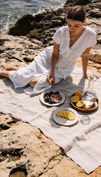 Woman enjoying fresh figs and citrus on rocky shore