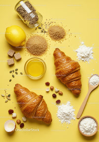 Fresh croissants with baking ingredients on yellow background