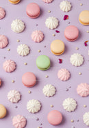 Colorful macarons and meringues on pastel purple background