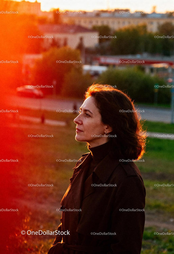 Zamyślona kobieta ciesząca się zachodem słońca na zewnątrz jesienią