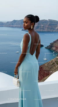 Elegant woman in light blue gown overlooking sea cliffs