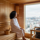 Woman Relaxing in Wooden Sauna with City View Window