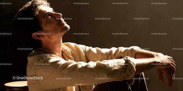Young man in soft light looking up thoughtfully