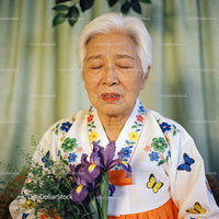 Elderly woman in traditional dress holding purple flowers