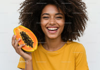 Smiling Woman Holding a Fresh Papaya with Black Seeds in Bright Yellow Shirt