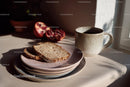 Coffee Cup with Sliced Bread and Pomegranate Halves in Sunlit Morning Scene