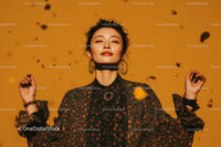 Stylish Woman with Curly Hair in Floral Blouse on Golden Background