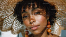 Young Woman with Large Straw Hat and Orange Earrings in Sunny Outdoor Setting