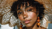 Young Woman with Large Straw Hat and Orange Earrings in Sunny Outdoor Setting