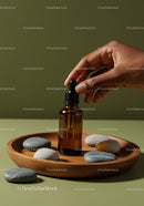 Elegant Brown Glass Dropper Bottle with River Stones on Wooden Tray