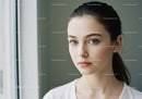 Elegant Young Woman with Blue Eyes Looking Out Window in Natural Light