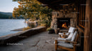 Cozy lakeside outdoor fireplace with wooden chairs and autumn foliage