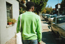 Young Man in Green Sweater Walking on Sunny City Street