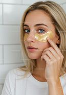 Young Woman Applying Gold Under Eye Patches for Youthful Skin