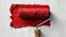 Red Paint Roller on White Wooden Surface for Wall Renovation