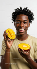 Young Man Smiling with Fresh Mango Slices in Bright Studio