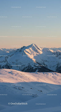 Snowy mountain peak glowing in soft evening light