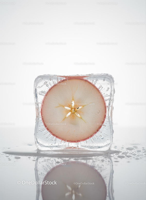 Fresh apple slice frozen within a clear ice cube