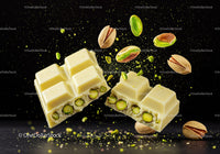 Broken white chocolate with whole pistachios on black background