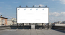 Large blank billboard on urban rooftop under blue sky