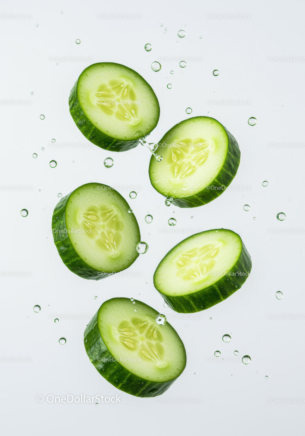 Fresh cucumber slices floating in clear water droplets