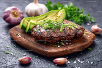 Juicy Grilled Steak with Avocado and Fresh Herbs on Wooden Board