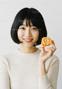 Young Asian Woman with Short Black Hair Holding Orange Citrus Fruit