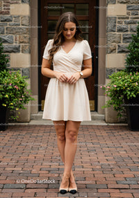 Elegant Young Woman in Beige Dress Standing on Brick Street
