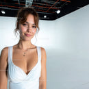 Young woman in white dress with jewelry smiling in studio