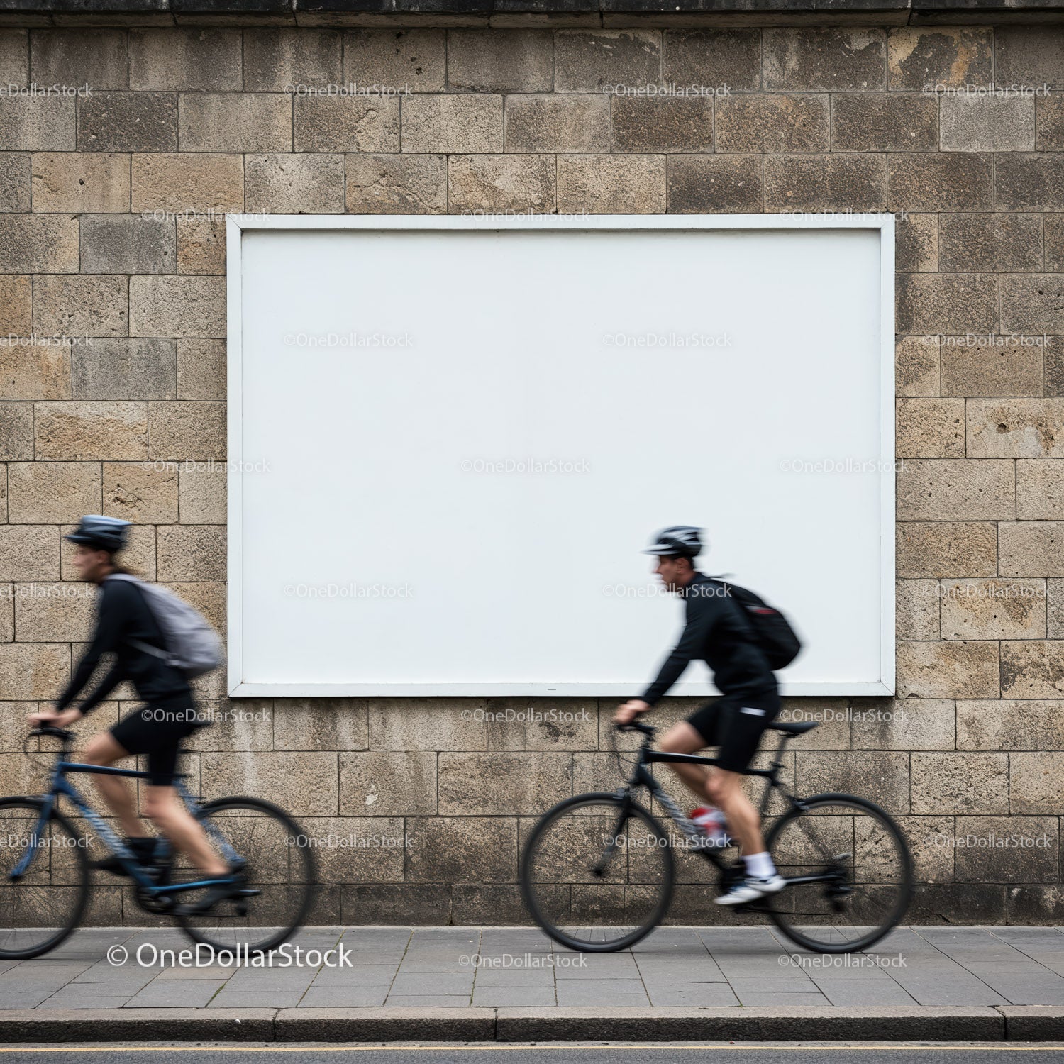 Dwóch rowerzystów przejeżdża obok pustego miejskiego billboardu