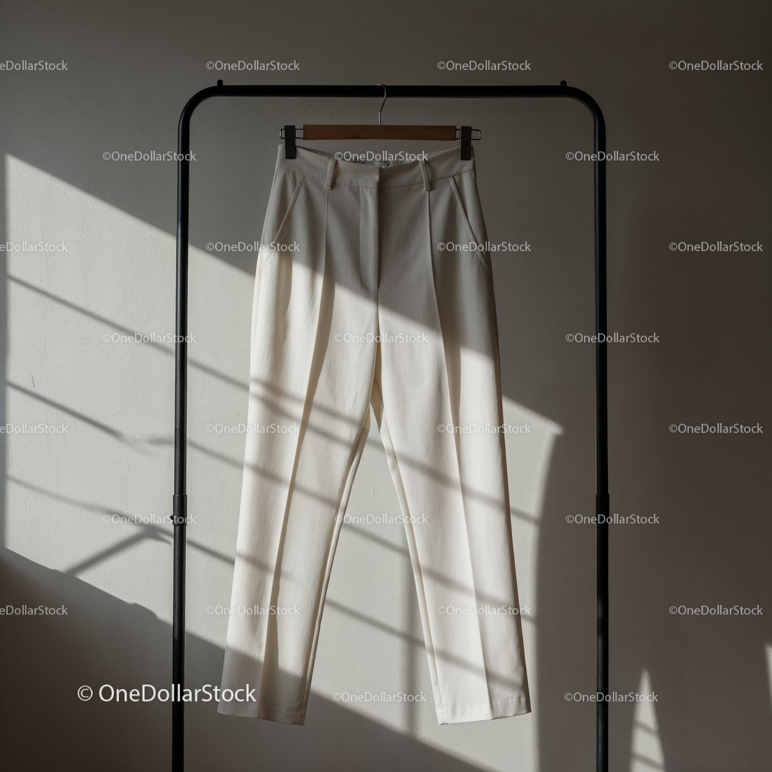 Minimalistyczne białe spodnie wiszące na czarnym wieszaku