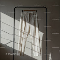 Minimalist white trousers hanging on black rack