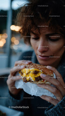 Young Woman Enjoying Cheeseburger During Sunset Outdoor Meal