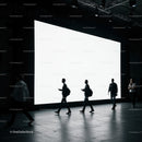 Silhouettes walking past large illuminated display screen