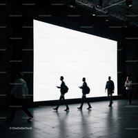 Silhouettes walking past large illuminated display screen