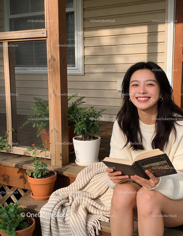 Smiling young woman enjoying her book outdoors