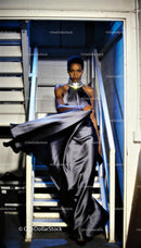 Elegant model descending stairs in flowing satin gown