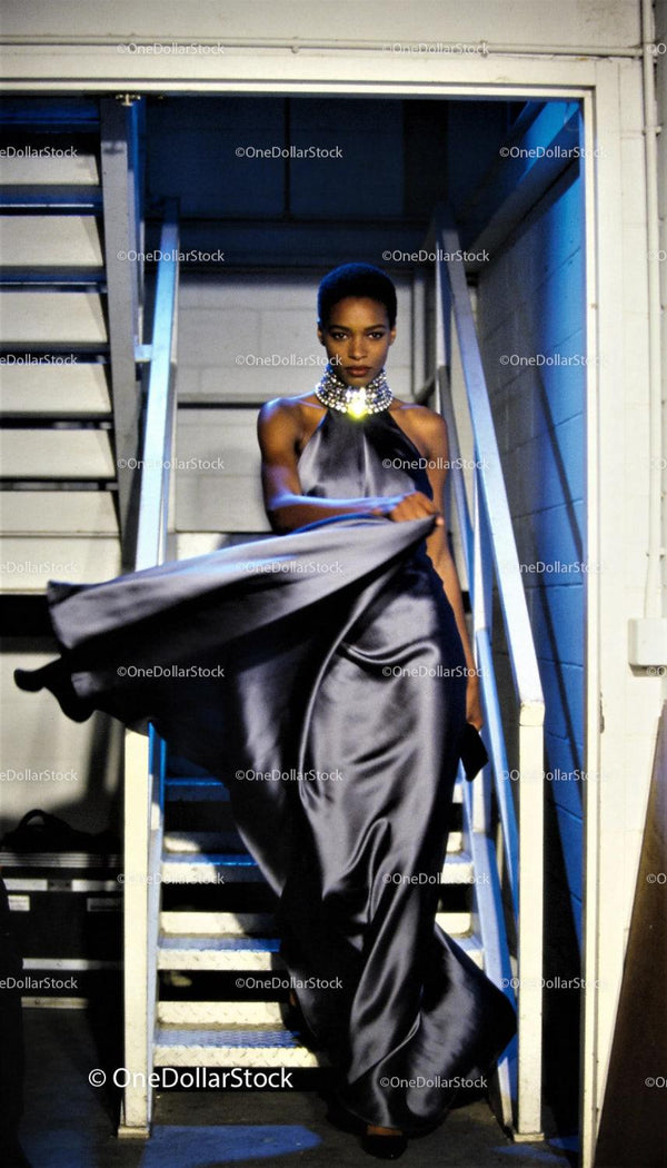 Elegant model descending stairs in flowing satin gown