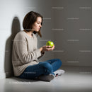 Young woman sitting on floor holding green apple