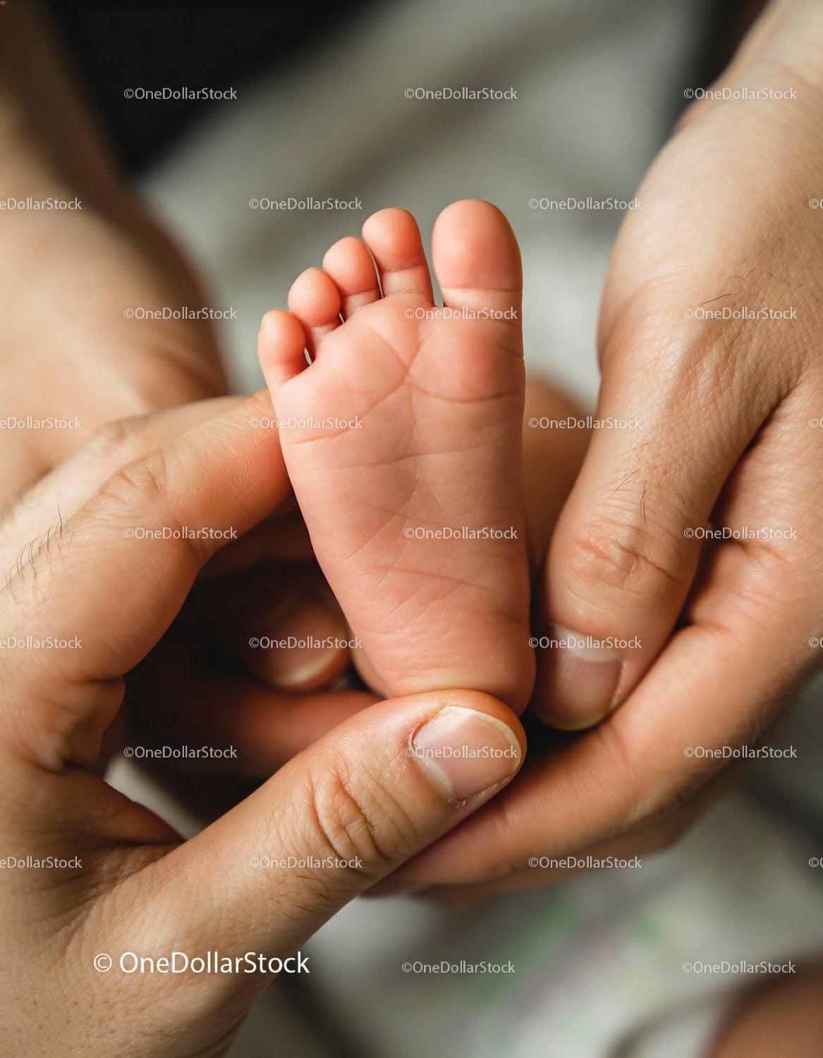 Close-up of parent's hands holding newborn baby foot