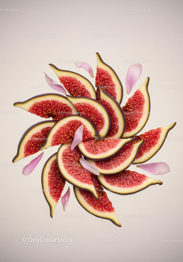 Fresh fig slices arranged with soft pink petals on beige