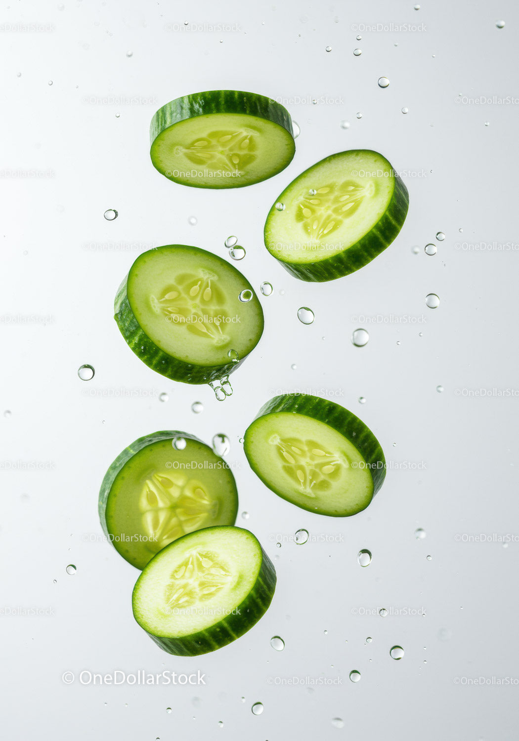 Fresh cucumber slices immersed in clear water droplets