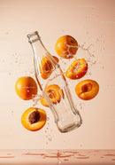 Fresh apricots splashing around glass bottle