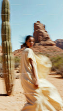 Elegant Woman in Flowing Dress Moving Through Desert Landscape