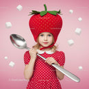 Little girl in strawberry hat holding giant spoon