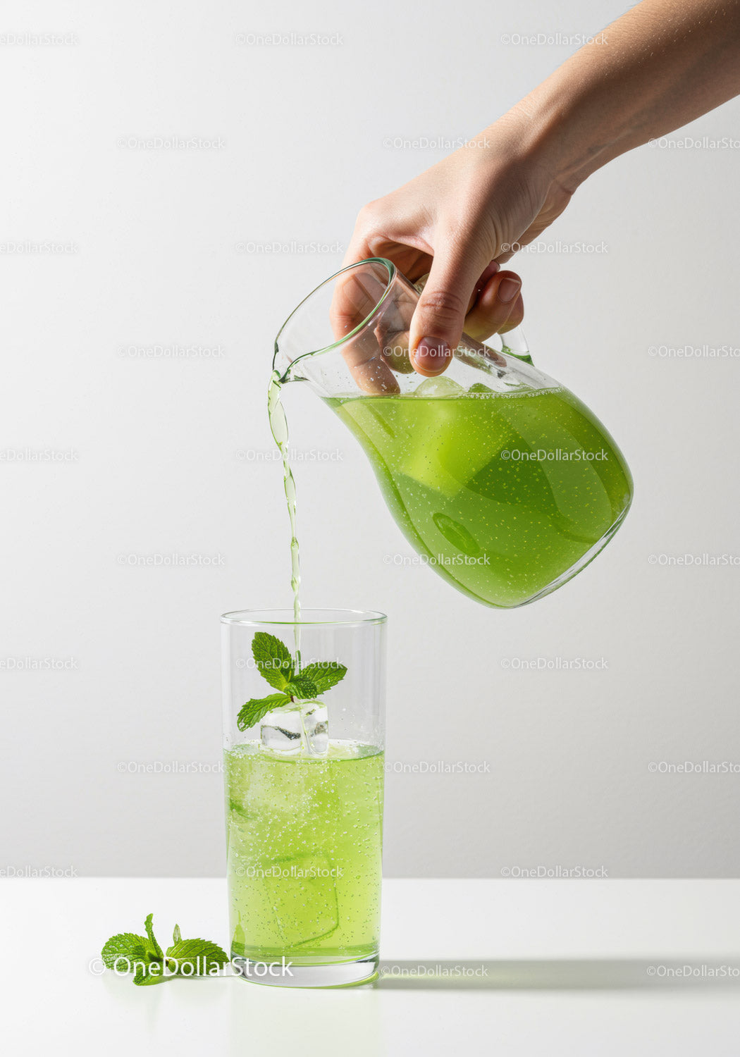 Refreshing green mint drink poured over ice cubes