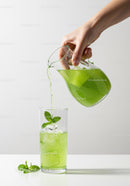 Refreshing green mint drink poured over ice cubes