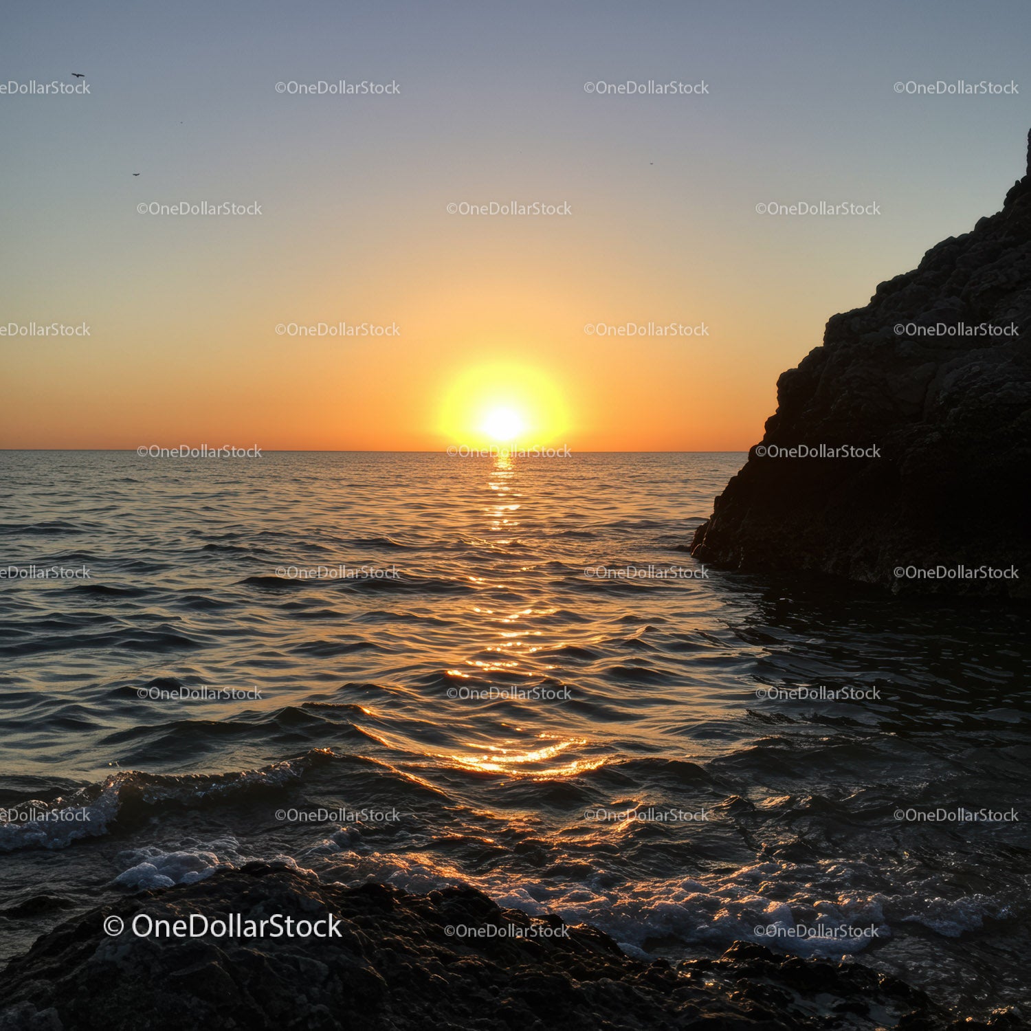 Beautiful Sunset Over Calm Ocean with Rocky Shore