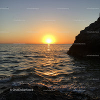 Beautiful Sunset Over Calm Ocean with Rocky Shore